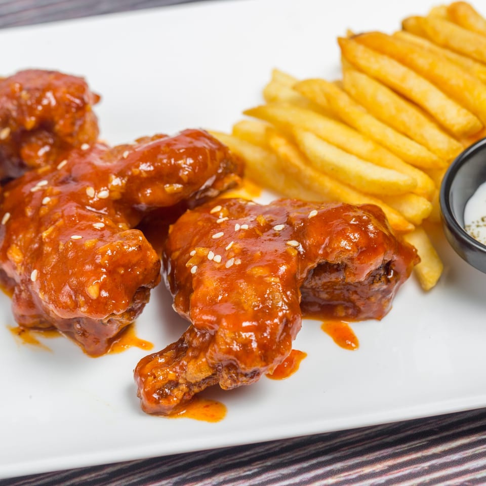 CFC Fried Chicken's spicy chicken wings with sesame seeds, golden french fries, and a dipping sauce.