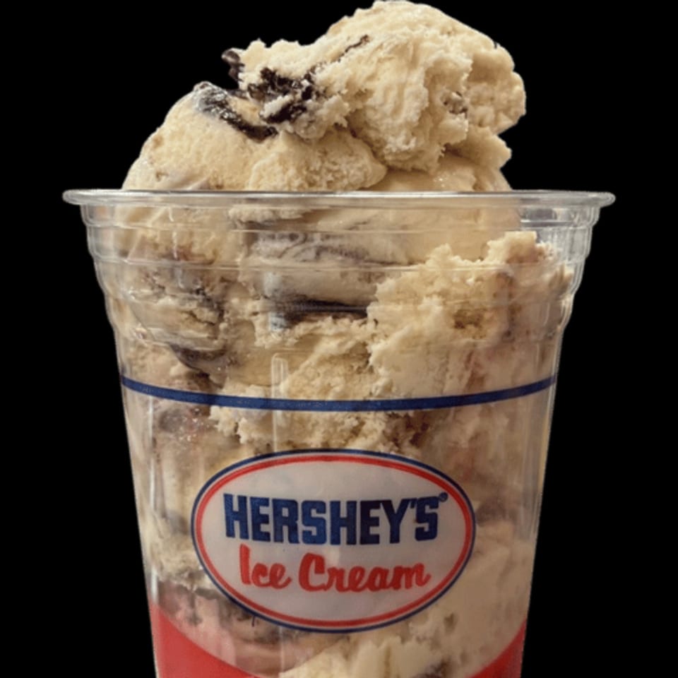 A clear plastic cup filled with Hershey's Cookies 'n' Creme ice cream against a black background.