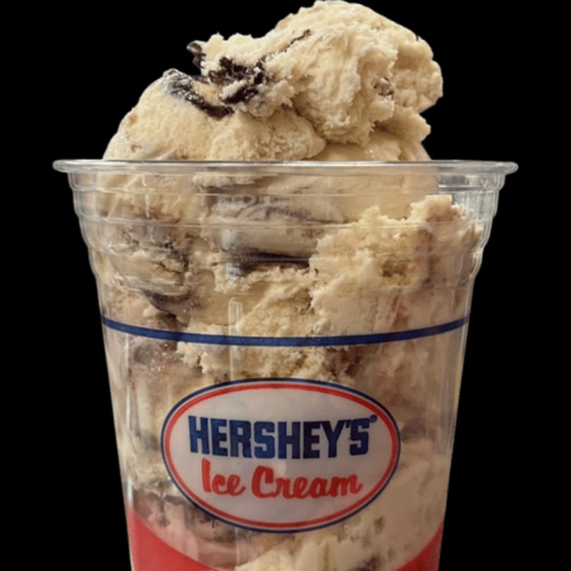 A clear plastic cup filled with Hershey's Cookies 'n' Creme ice cream against a black background.